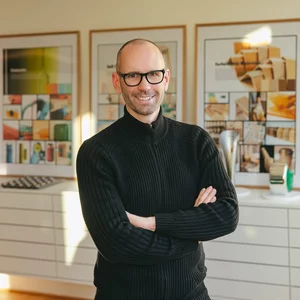Vorwerk: Photo: The photo shows an upper body cut-out of Jan Delfs, Vorwerk Chief Designer, with his arms crossed in front of his stomach, smiling into the camera.