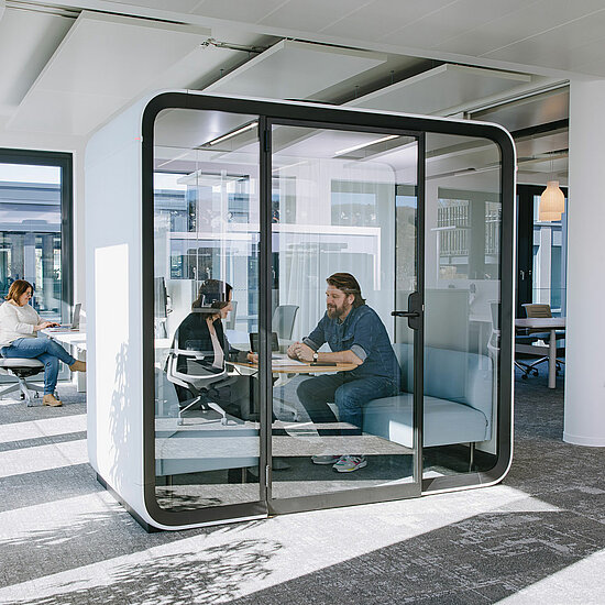 Vorwerk: Photo: Two people sit in a soundproof meeting box, also known as a think tank, and discuss a topic.