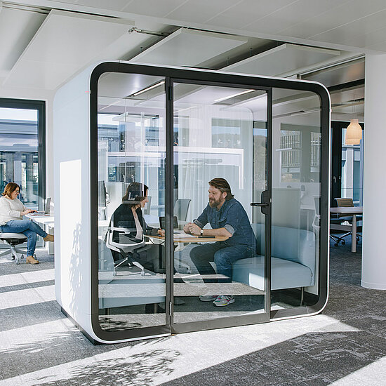 Vorwerk: Photo: In a very modern office, there is a glass meeting box in which two people are talking without anything leaking out.