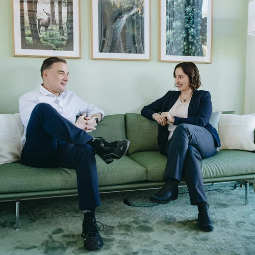 Vorwerk: Foto: Zwei Personen sitzen auf einem grünen Sofa in einem Büro.