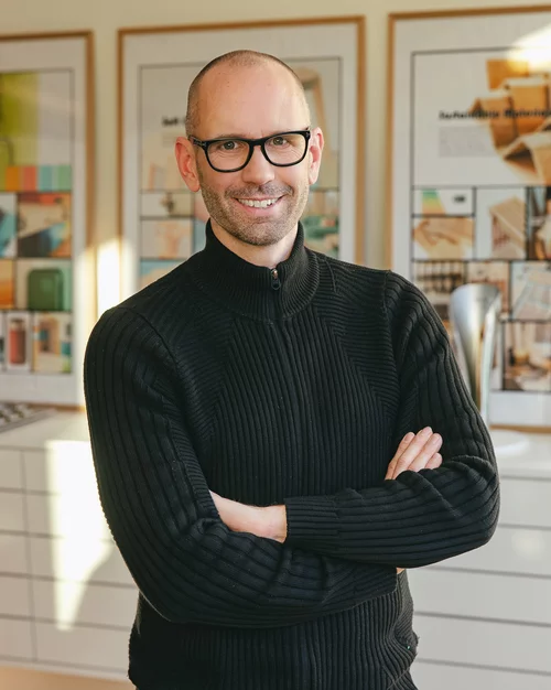 Vorwerk: Foto: Das Foto zeigt einen Oberkörper-Ausschnitt von Jan Delfs, Vorwerk Chefdesigner, mit vor dem Bauch verschränkten Armen, der in die Kamera lächelt.