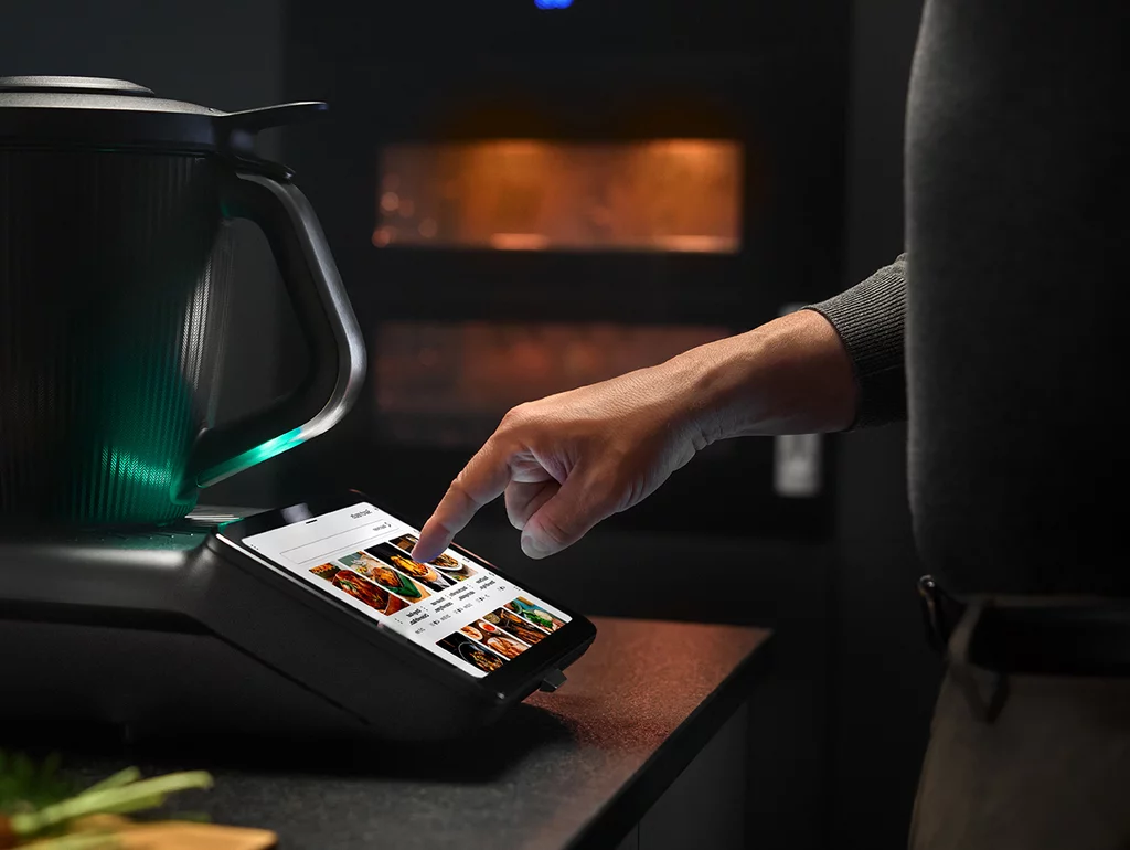 Vorwerk: Photo: The picture shows the new black Thermomix® TM7, which glows green, from the side.