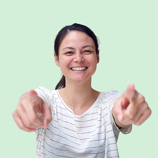 Vorwerk: Photo: A woman with dark hair laughs and points both index fingers at the camera.