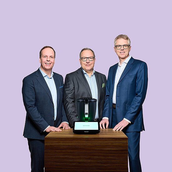 Vorwerk: Photo: This photo shows the Vorwerk Executive Board: Hauke Pausch on the left, Dr. Thomas Stoffmehl, Spokesman of the Executive Board, in the middle and Dr. Thomas Rodemann on the right. In front of them on a wooden table is the Thermomix TM7.